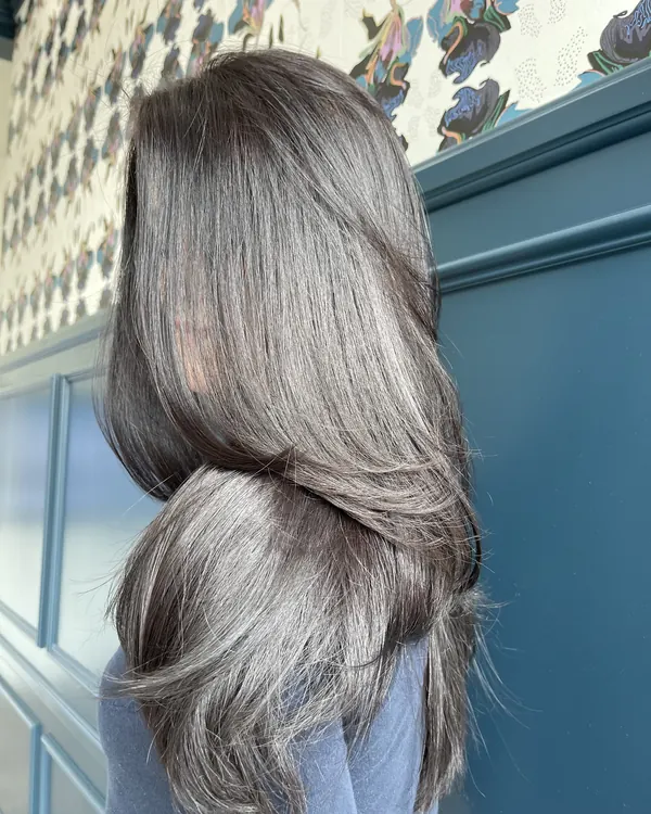 Glossy dark brunette hair with a voluminous layered blowout by Aprille at Novum Hair Studio