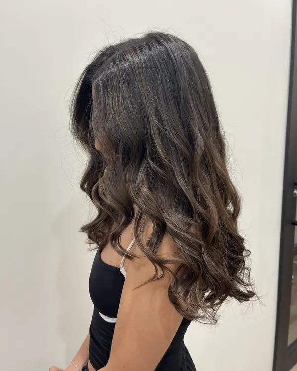 Rich dark brunette hair with soft brown dimension and loose waves by Aprille at Novum Hair Studio