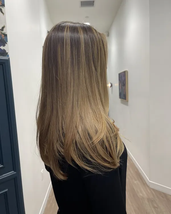 Long brunette hair with soft dimensional caramel highlights and seamless layers by Aprille at Novum Hair Studio